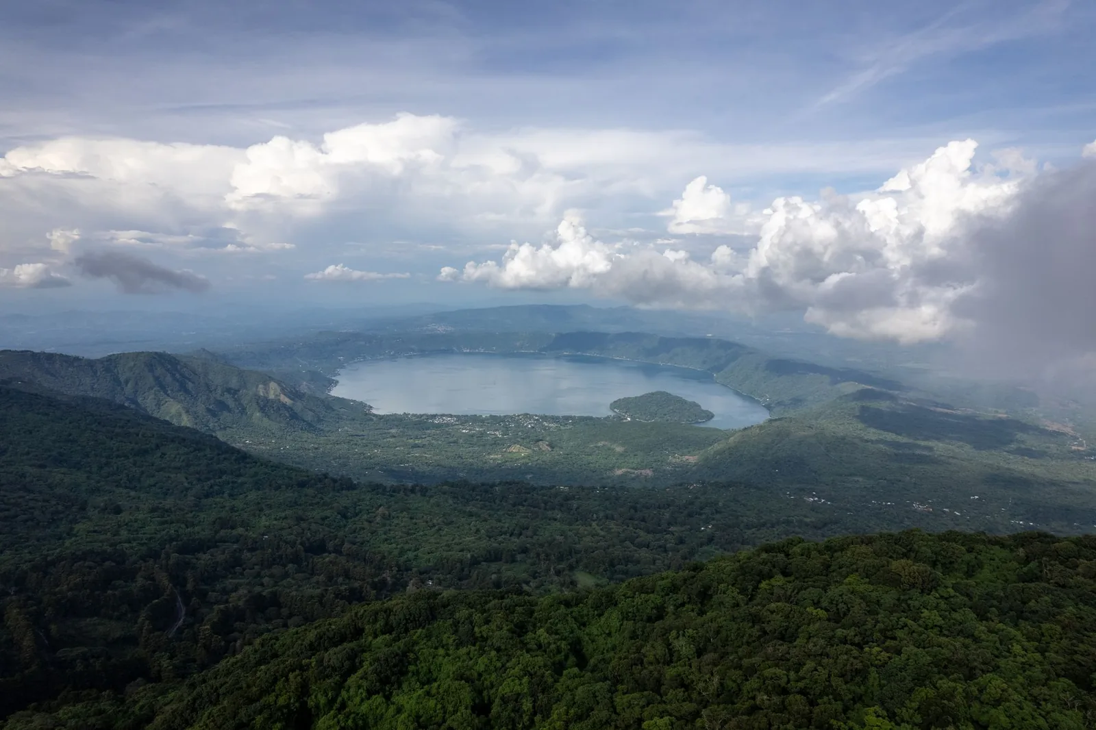 Lake Coatepeque, a crater lake in western El Salvador, seen from above with green hills and clouds