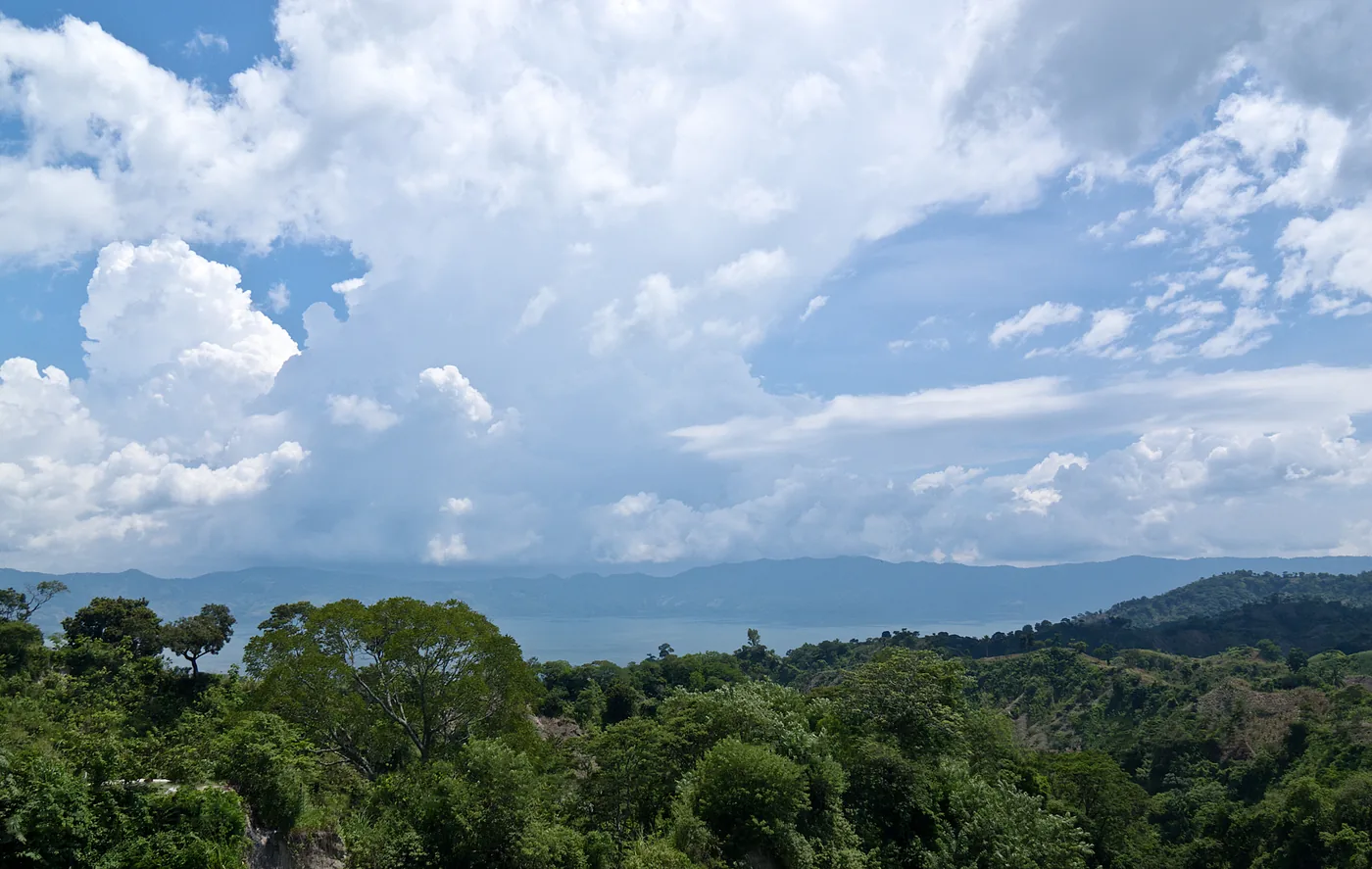 Green forested hills and tall clouds above the Lake Ilopango area in El Salvador